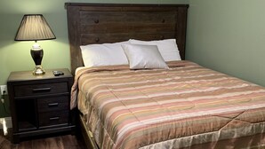 A bedroom with a wooden bed, a nightstand with drawers, a lamp, and a wall socket. - 405 S. Madison, Suite A (Watkins Glen)