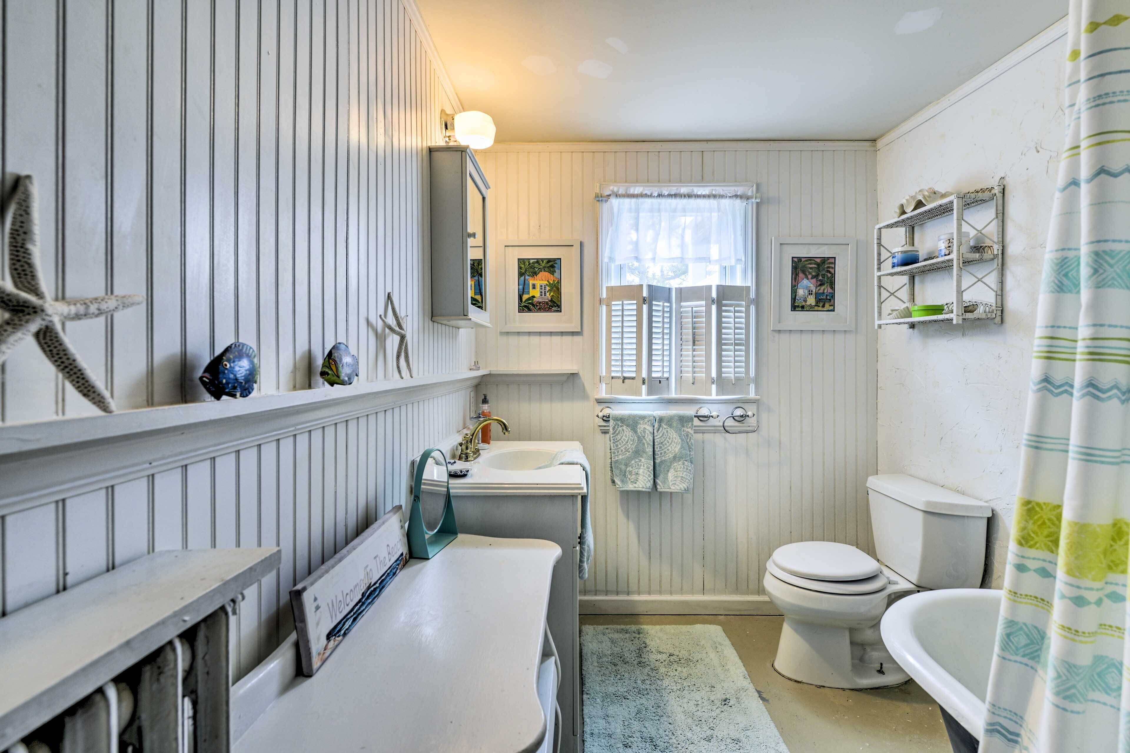 Une salle de bain avec un meuble-lavabo blanc, un évier, des toilettes et un rideau de douche.