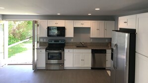 A modern kitchen with white cabinets, stainless steel appliances, and a view of the outdoors. - 304 3rd Street, Suite A (Watkins Glen)