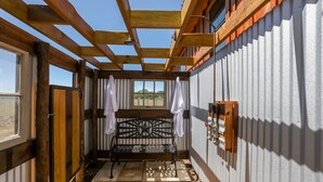 Une pièce rustique en bois, avec un banc, une fenêtre et une porte.