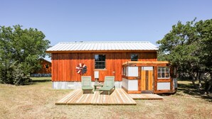 Une cabane rustique en bois, dotée d’un toit en métal, d’un moulin à vent et d’une petite structure en bois avec une fenêtre.