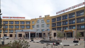 Un hotel a più piani con un cortile centrale caratterizzato da una fontana e piante in vaso.