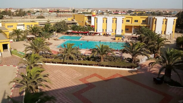 Un hotel con piscina circondata da palme e un cortile.
