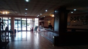 Un'ampia hall con reception, un'ampia finestra e un pavimento piastrellato.