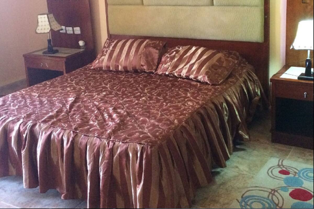 Ein Hotelzimmer mit einem großen Bett, einem Nachttisch, einer Lampe und einer Kommode.