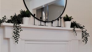 Una chimenea blanca con pantalla negra, flanqueada por paredes blancas y un suelo de madera.