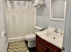 A bathroom with a shower, toilet, sink, and a towel rack.