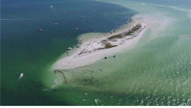 An aerial view of a coastal area with a sandy beach and clear waters. - Coastal Escape Awaits: Enjoy a Complimentary Pontoon Boat Adventure! (New Port Richey)