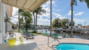 A pool area with a view of the water, palm trees, and boats. - Coastal Escape Awaits: Enjoy a Complimentary Pontoon Boat Adventure! (New Port Richey)