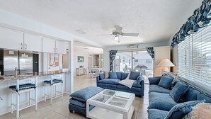 A spacious living area with a kitchen, a dining area, and a seating area with a sofa and ottoman. - Coastal Escape Awaits: Enjoy a Complimentary Pontoon Boat Adventure! (New Port Richey)