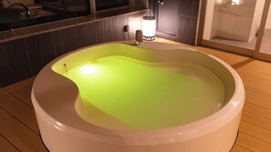 A large bathtub filled with water, a faucet, and a wall-mounted light fixture. - Ooedo Onsen Monogatari Premium Matsunoi (Minakami)