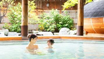 Una piscina exterior con agua cristalina, rodeada de construcciones de madera y vegetación.