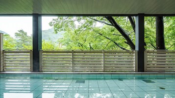 Una piscina techada con vistas a exuberante vegetación y árboles.
