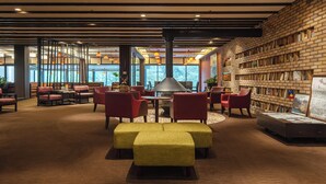 A modern interior with seating areas, a central table, and a brick wall with bookshelves.