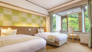 A hotel room with two beds, a wooden headboard, a window with a view of greenery, and a chair.