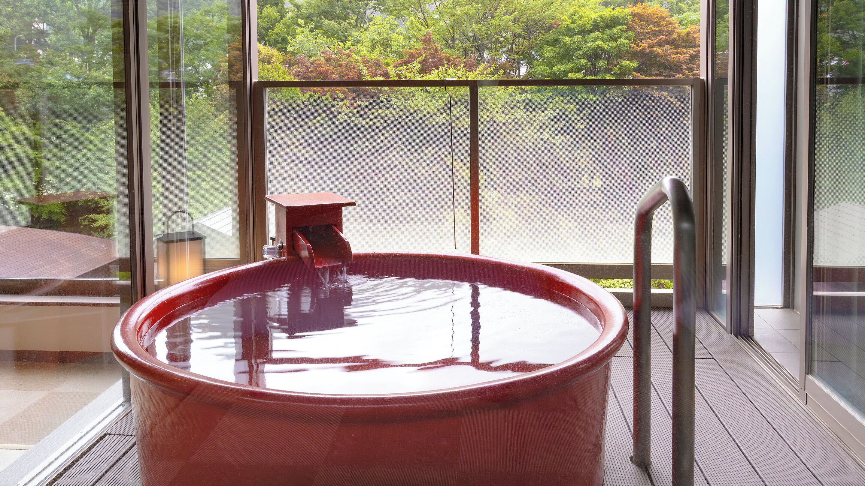 A hot tub on a balcony with a view of trees.