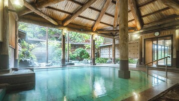 Una construcción de madera tradicional con piscina, escalones de piedra y una puerta de madera.