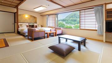 A traditional Japanese-style room with tatami flooring, a bed, a sofa, a table, and a TV.