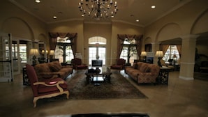 A spacious living room with a large chandelier, comfortable seating, and large windows allowing natural light. - Universal,Disney World,Convention Center,Executive Luxury 5*Vista Cay Villa/Pool (Orlando)