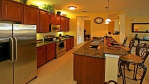 A modern kitchen with stainless steel appliances, wooden cabinets, and a central island with bar stools. - Universal,Disney World,Convention Center,Executive Luxury 5*Vista Cay Villa/Pool (Orlando)
