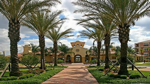 A pathway leading to a building with a central tower, surrounded by palm trees and well-maintained gardens. - Universal,Disney World,Convention Center,Executive Luxury 5*Vista Cay Villa/Pool (Orlando)