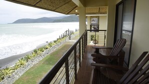 A balcony with a view of the ocean, a wooden table, and a chair. - Nalu Surf Camp (Baler)