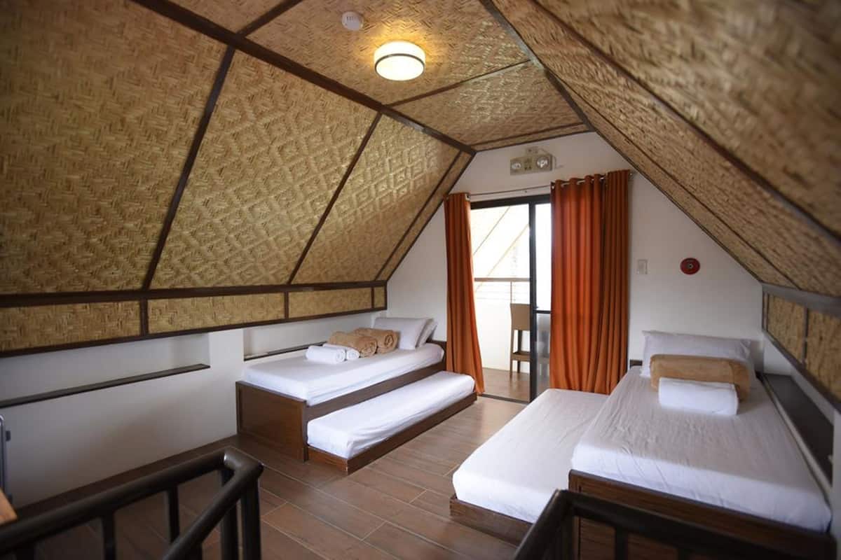 Habitación con dos camas, techo de madera y vista al exterior.