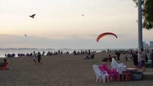 Een strand met mensen, stoelen en een parasail.