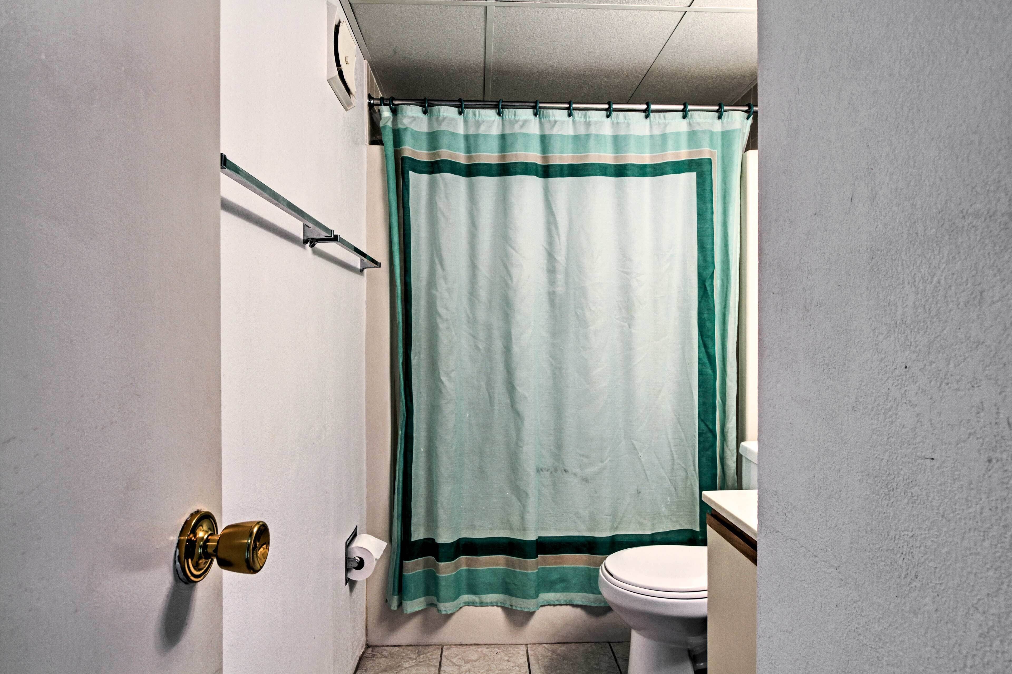Et badeværelse med bruseforhæng, toilet og en dør med en messinggreb.