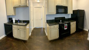 A kitchen with white cabinets, a black microwave, a black refrigerator, and a stove. - Watkins Glen 3-Bedroom Suites Unit 4 (Watkins Glen)