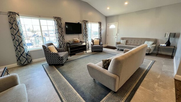 A spacious living room with a large window, a flat-screen TV, and a sofa. - 405 S. Madison, Suite B (Watkins Glen)