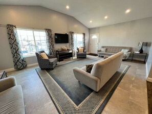 A spacious living room with a large window, a flat-screen TV, and a sofa. - 405 S. Madison, Suite B (Watkins Glen)