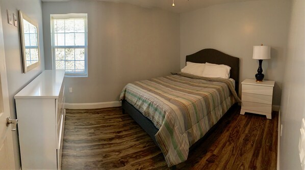 A bedroom with a bed, nightstand, dresser, and window with blinds. - 405 S. Madison, Suite B (Watkins Glen)