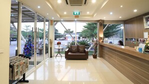 A reception area with a wooden reception desk, a brown leather sofa, and a Christmas tree visible through the glass doors.