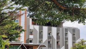 A multi-story building with a modern design, featuring balconies and a covered entrance area.
