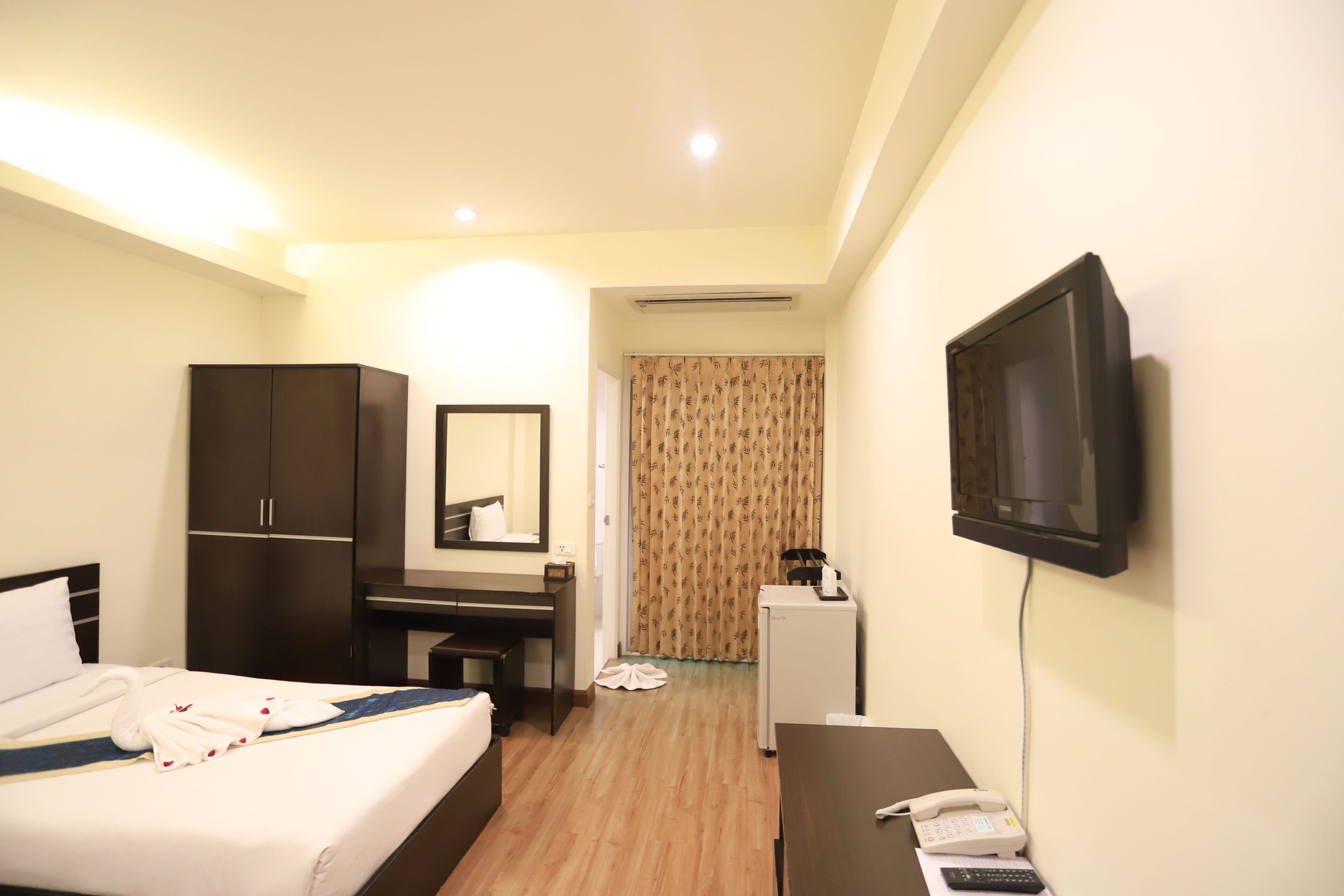 Una habitación de hotel con una cama, un escritorio, una silla, un televisor y un teléfono.