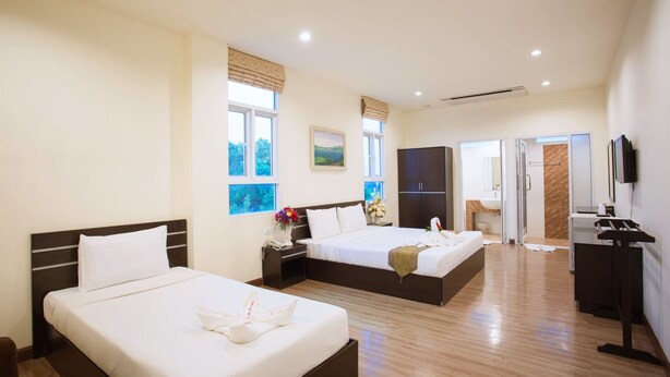 A hotel room with two beds, a TV, a desk, and a bathroom.