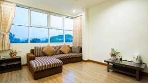 A living room with a sofa, a coffee table, and a window with curtains.