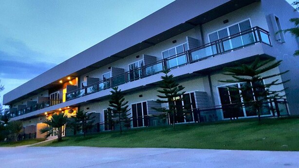 A multi-story hotel with balconies, a flat roof, and a well-maintained lawn. - Hadthong Resort (Pak Phayun)