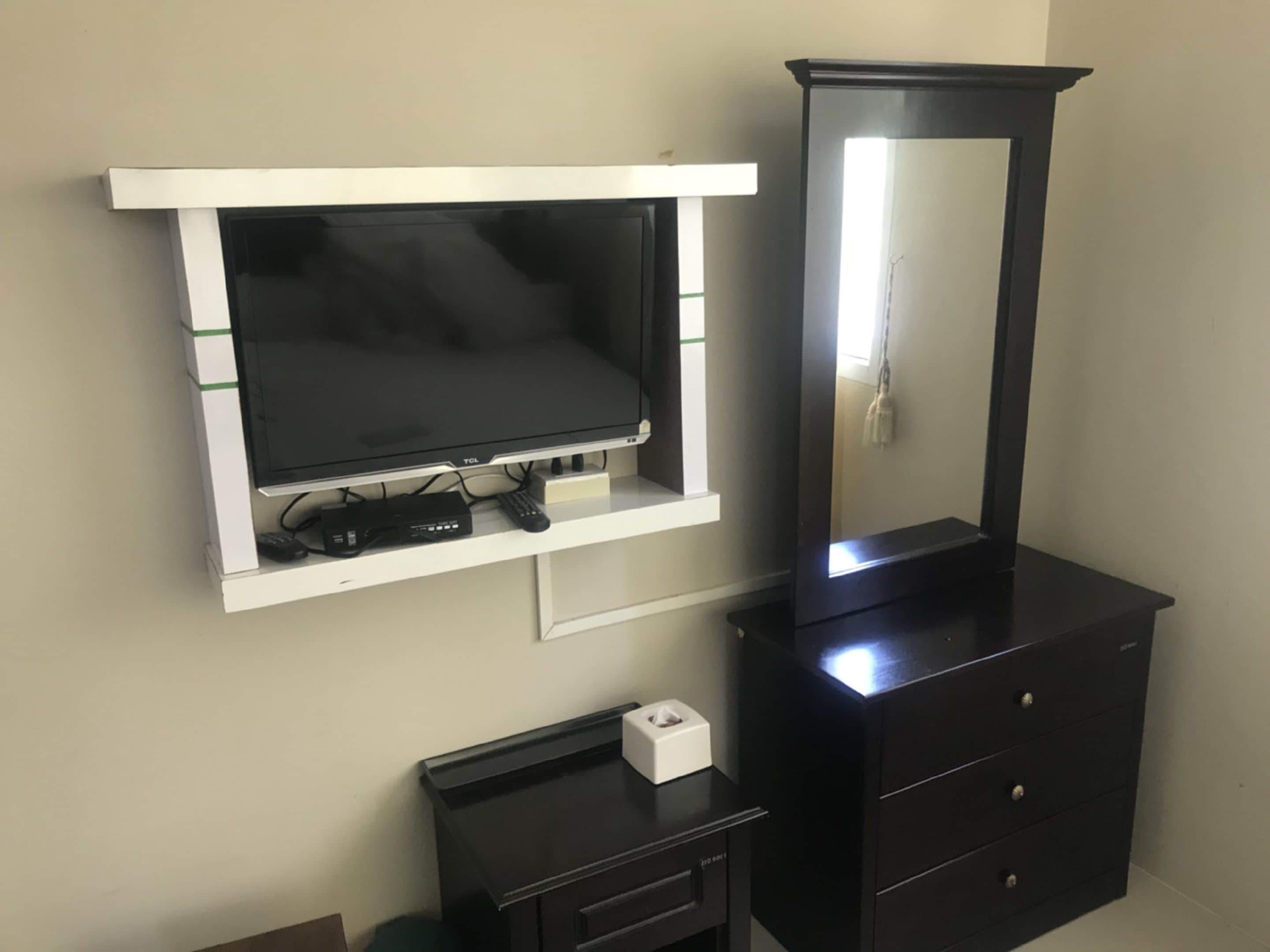 A TV mounted on a white shelf with a black entertainment unit below.