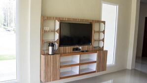 A modern entertainment unit with a flat-screen TV, built-in shelves, and a coffee maker. - Hadthong Resort (Pak Phayun)