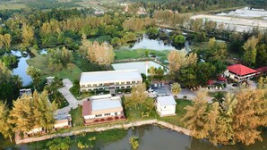 An aerial view of a resort with multiple buildings, a large body of water, and surrounding greenery. - Hadthong Resort (Pak Phayun)
