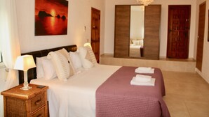 A hotel room with a large bed, a bedside lamp, a painting on the wall, a mirror, and a wooden door. - Beautiful 3 bed,2 bath villa with private pool, views, a/c,wifi,new full kitchen (Alacant)