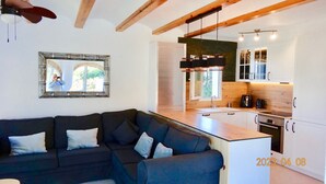 A modern living room with a dark-colored sofa and a dining area with a kitchen. - Beautiful 3 bed,2 bath villa with private pool, views, a/c,wifi,new full kitchen (Alacant)