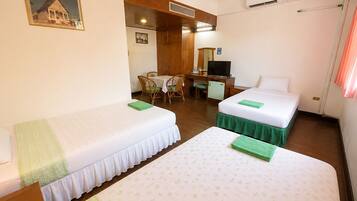 A hotel room with two beds, a desk, a chair, a television, and an air conditioning unit.