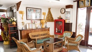 Una habitación con muebles de mimbre, un armario rojo y objetos decorativos en las paredes.