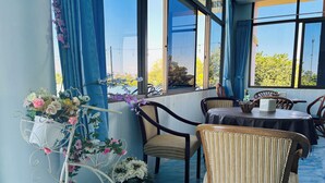 Un comedor con mesas y sillas, un arreglo floral decorativo y ventanas amplias con vistas.