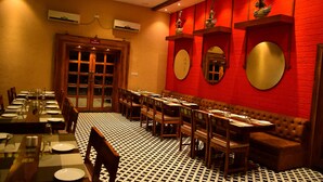 Un restaurante con una larga mesa común, cabinas individuales y un suelo estampado.