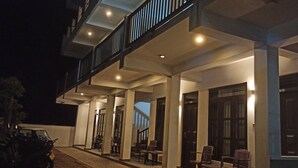 A hotel exterior at night with a covered outdoor seating area, columns, and a staircase leading to an upper level. - Sailors Mirissa (Mirissa)