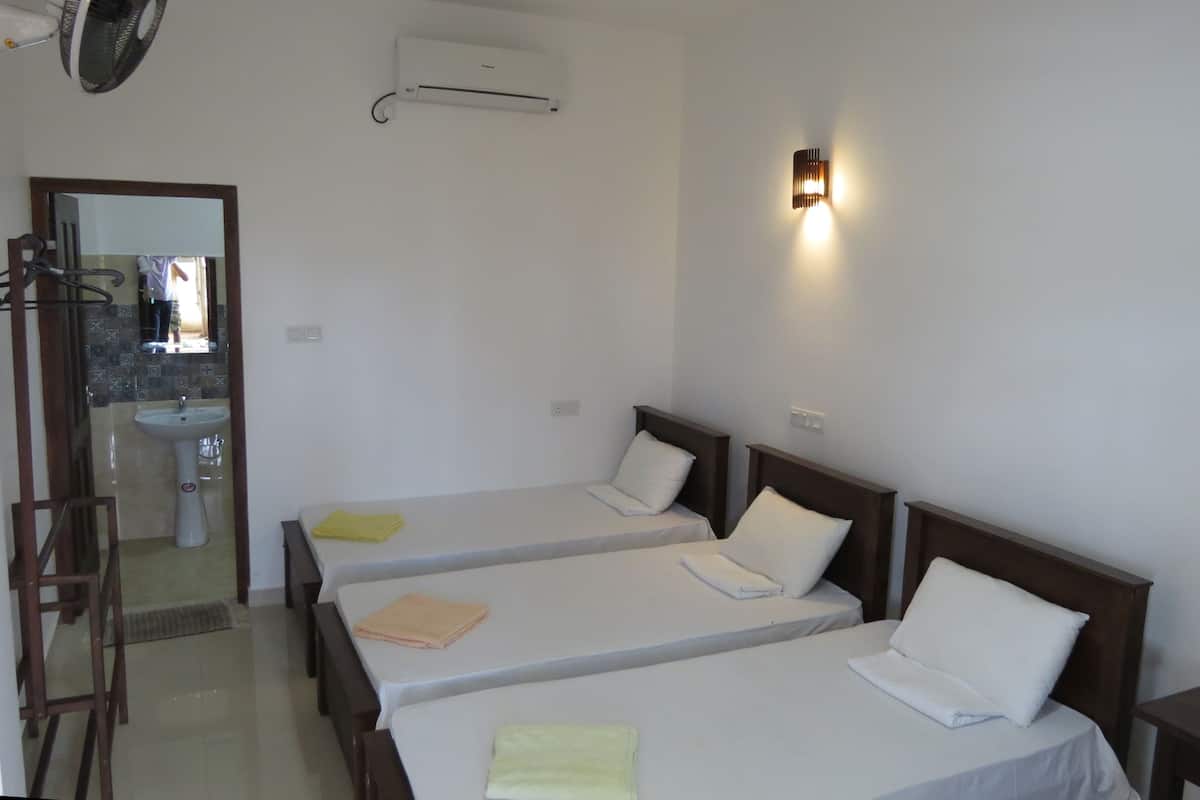 A hotel room with two single beds, a sink, and a mirror.